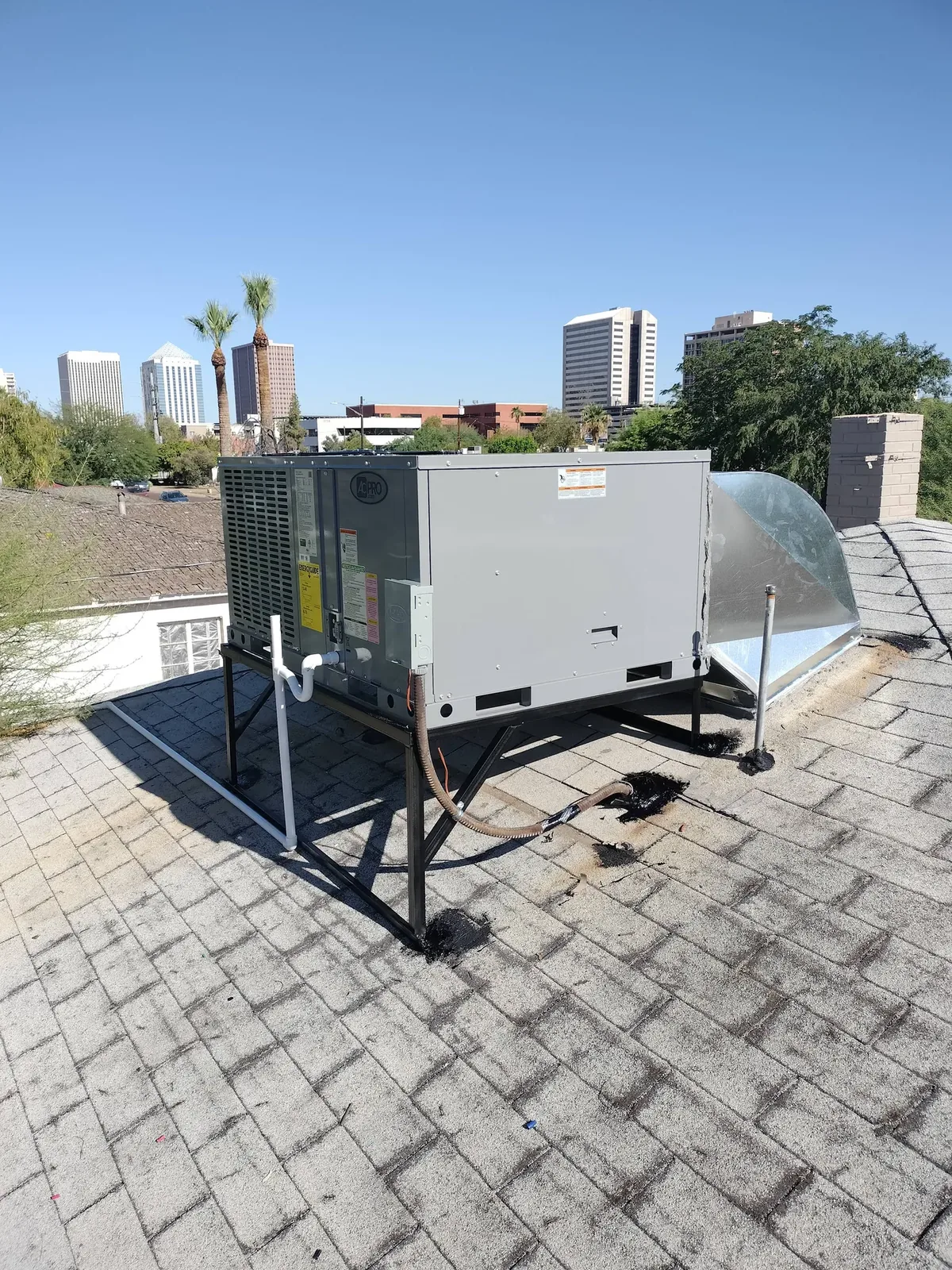 Rheem rooftop packaged A/C unit installed on a Phoenix home with the downtown skyline behind it